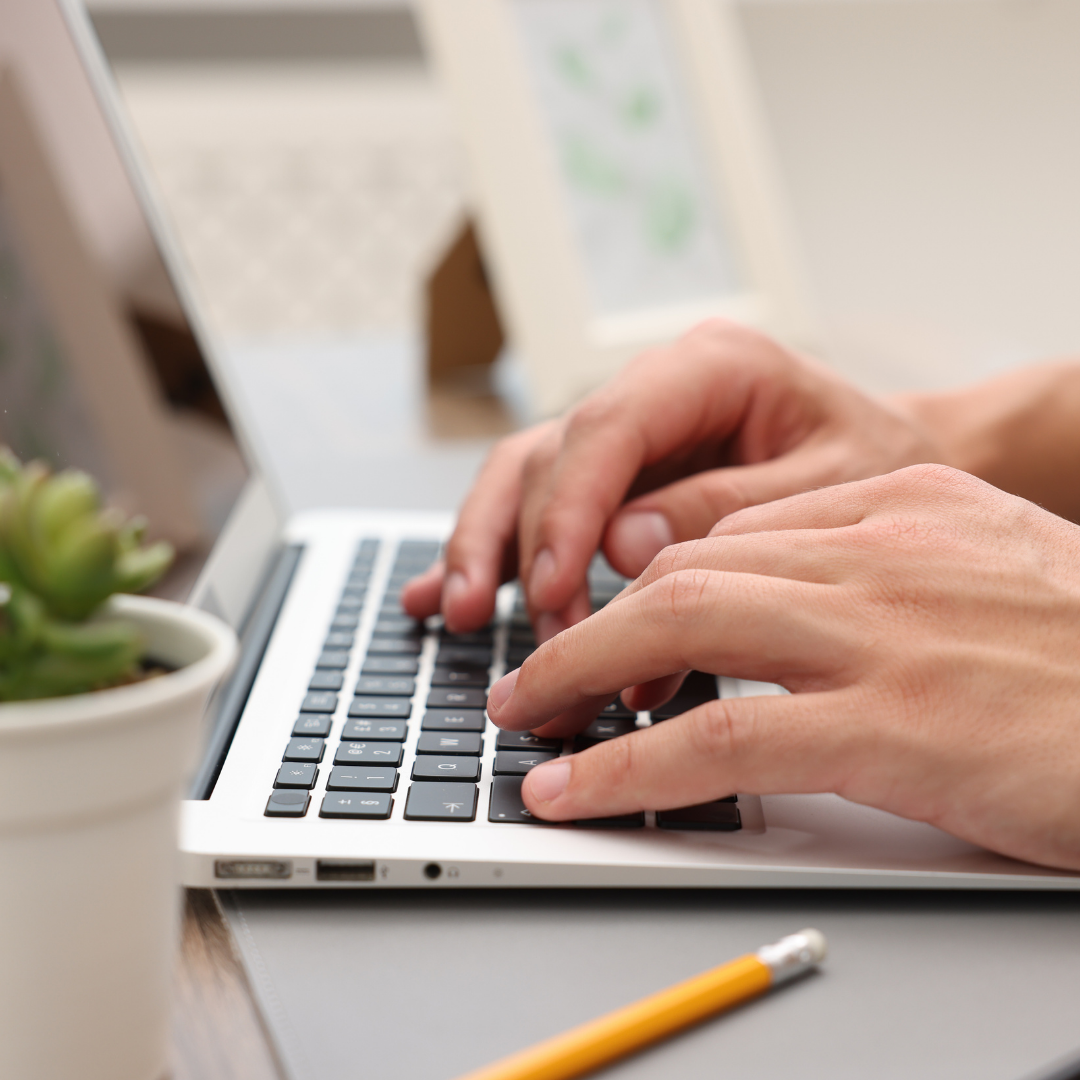 Close-up of hands typing on a laptop keyboard while writing B2B content