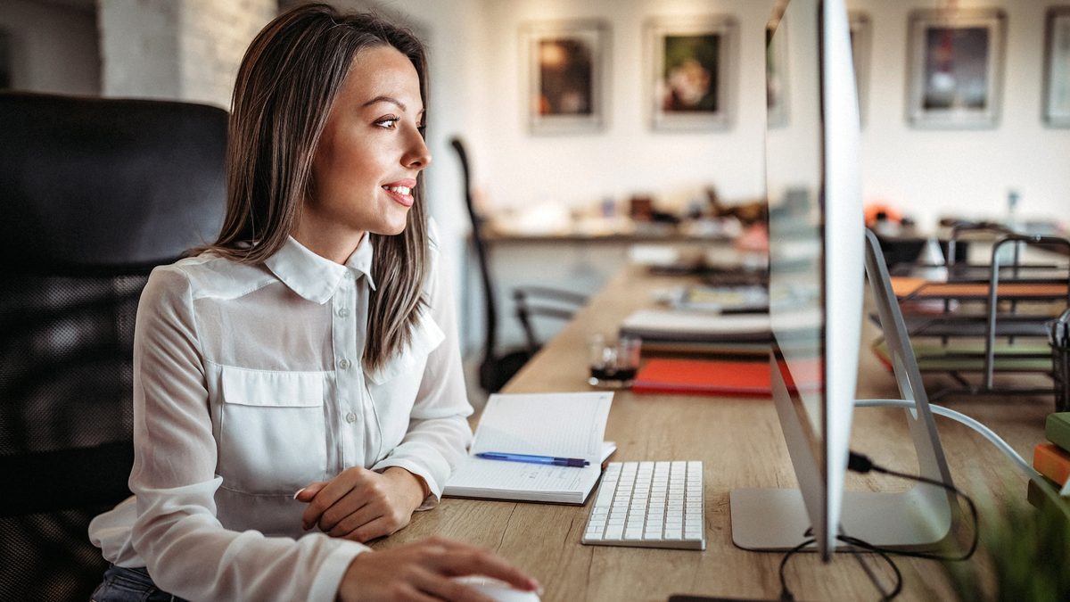 A marketer working at a desktop computer in an open-plan office