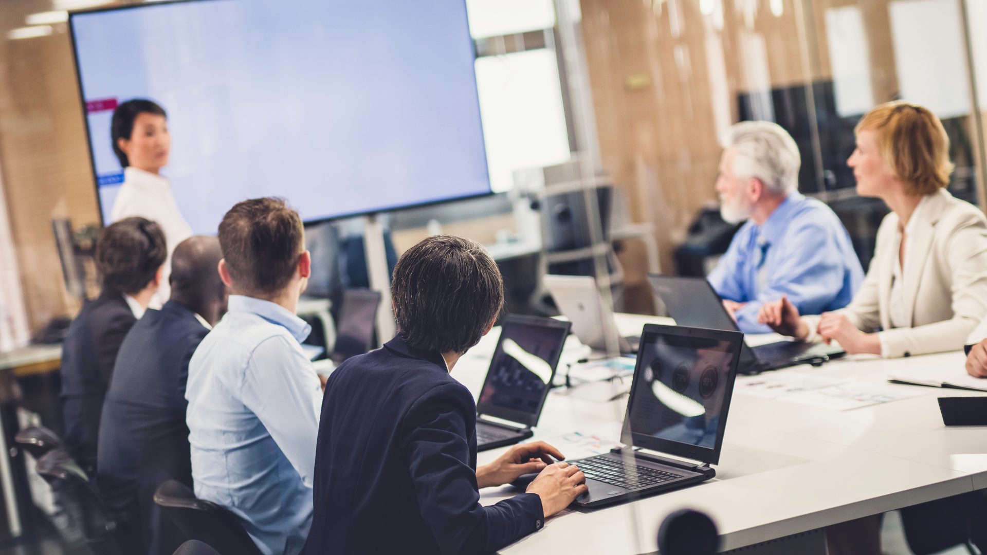 A team in a meeting looking at a blue presentation screen