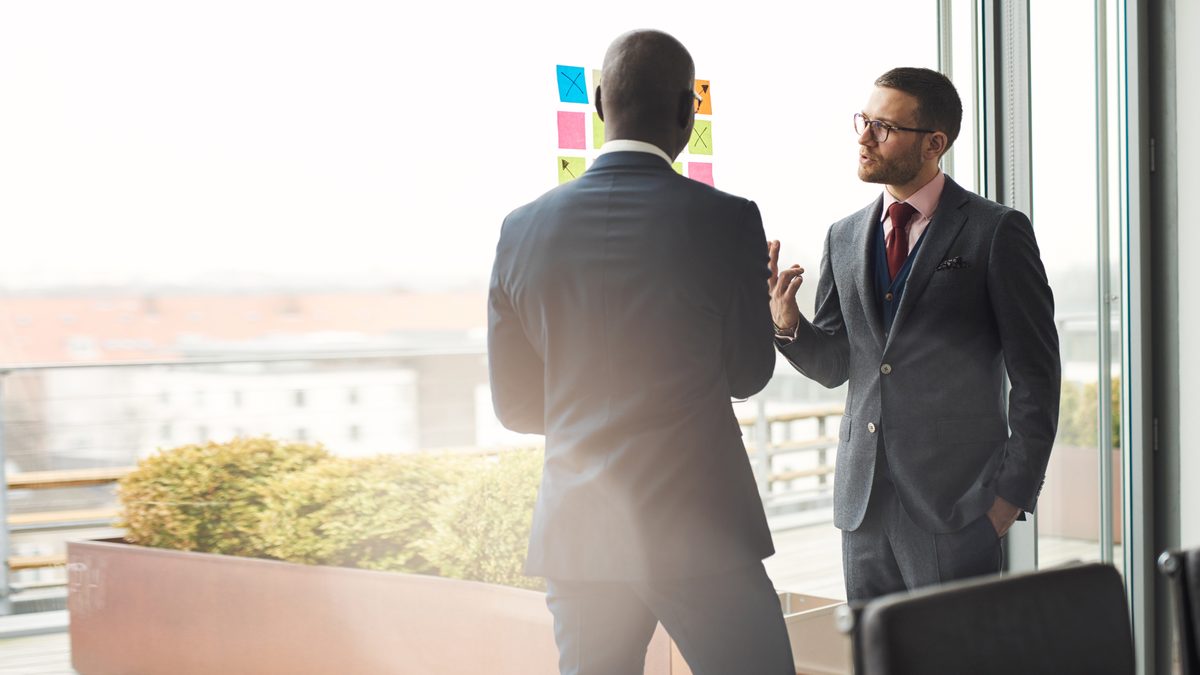 A professional presenting from a laptop during a boardroom meeting with colleagues